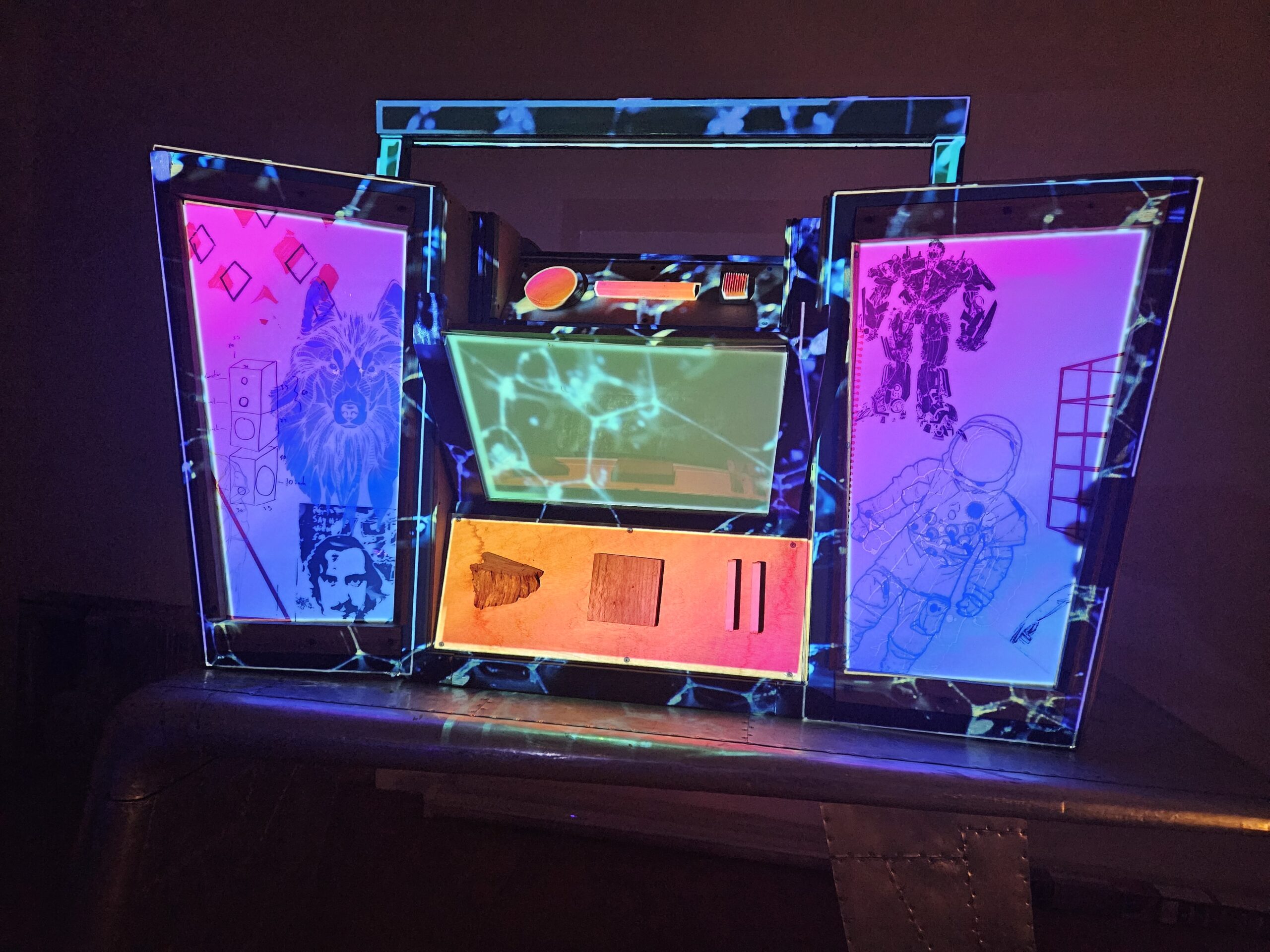 Sculptural Nicebox lightbox in boombox form: central console of marbled timber and ply opens to reveal two side panel lightboxes glowing magenta and cyan, screen-printed with wolf, robot, astronaut and Vultures Nest motifs.