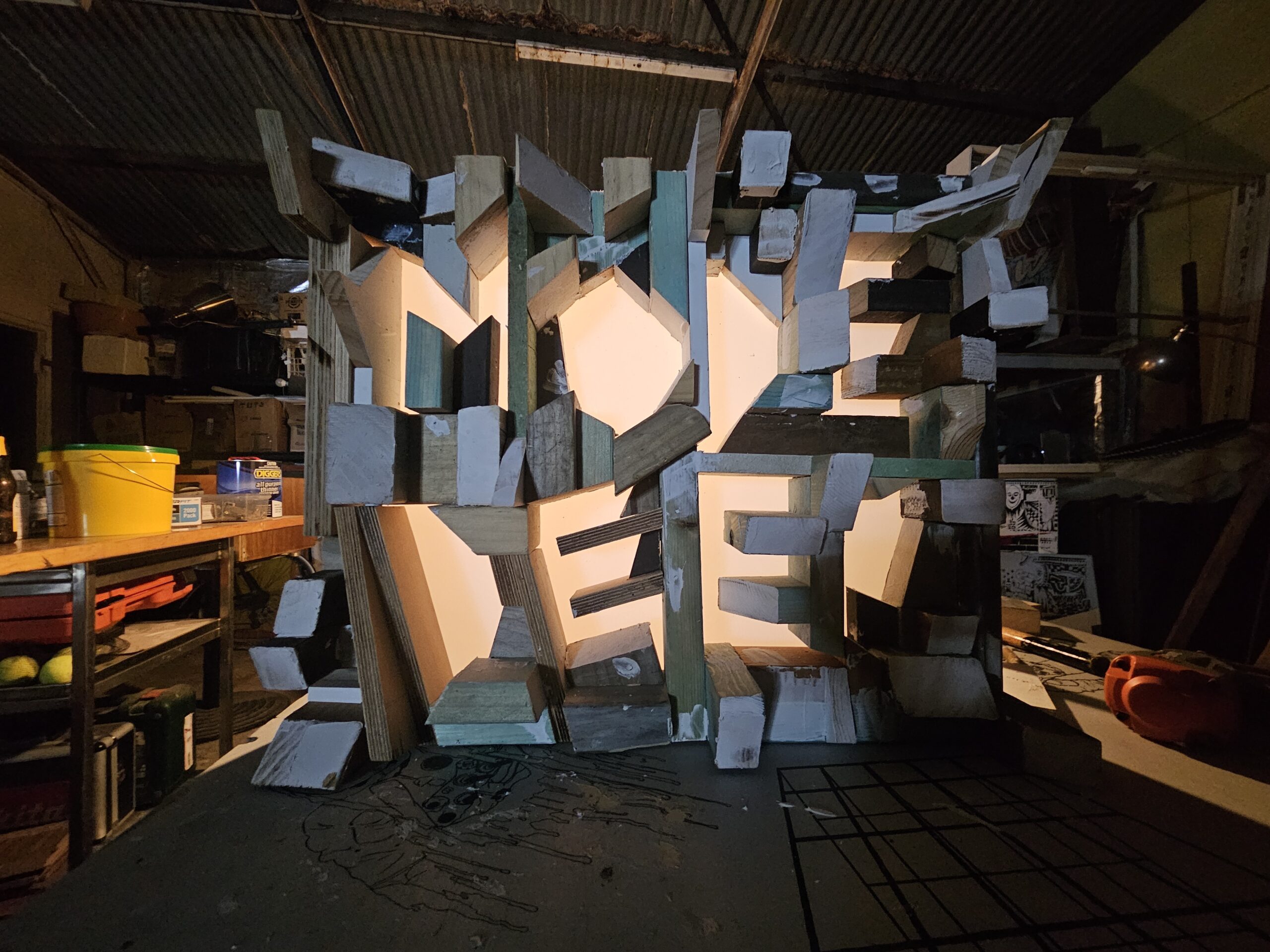 Mode Deep sculptural illuminated lightbox by Nicebox, hand-built from layered reclaimed timber blocks with deep orange light bleeding through the gaps, photographed in the Vultures Nest studio.